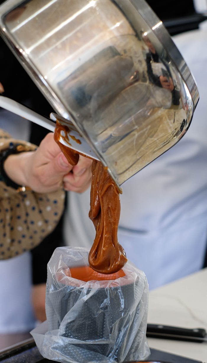 Craftsperson pouring caramel mixture into a mold during an artisan workshop in Chicago.