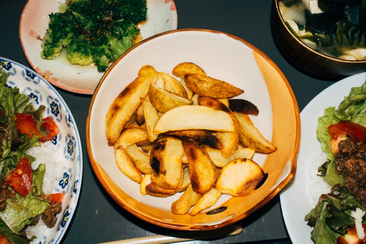 Delicious meal featuring crispy potato wedges, fresh salads, and vibrant broccoli sides.