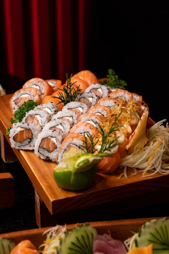 Delicious sushi platter with fresh salmon, garnished with herbs, lime, and vegetables. Perfect for gourmet dining.