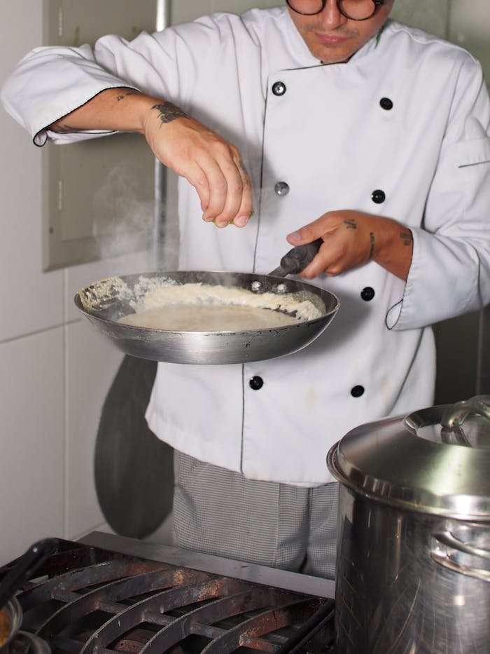 Chef seasoned dish in modern kitchen, showcasing culinary skills and techniques.