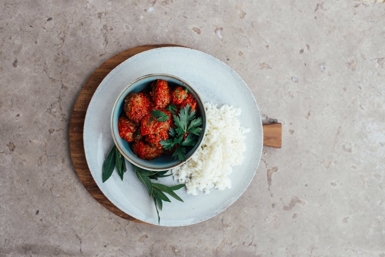 Delicious Asian-style meatballs with rice, garnished with herbs, on a textured plate.